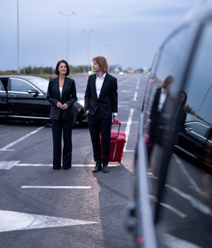 Chauffeur privé accueillant des passagers avec bagage pour un transport vers l’aéroport